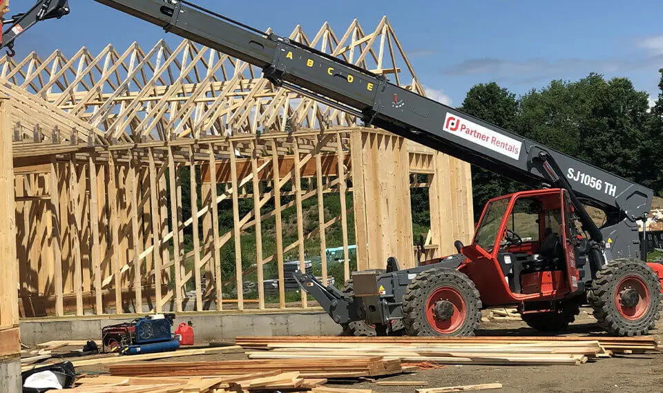 A photo of a reach forklift at a job site of a new building being constructed.