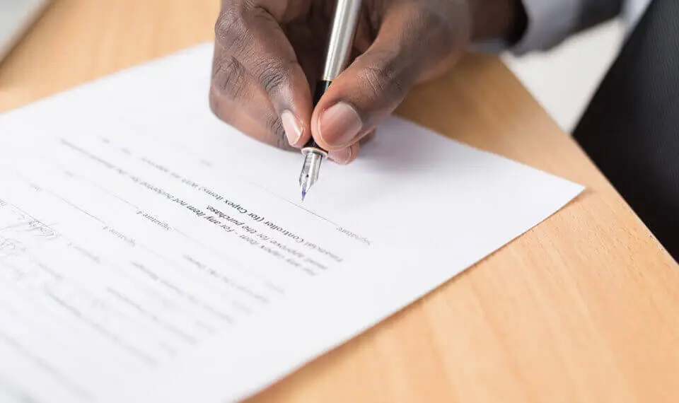 A photo of someone holding a pen and about to sign a contract.