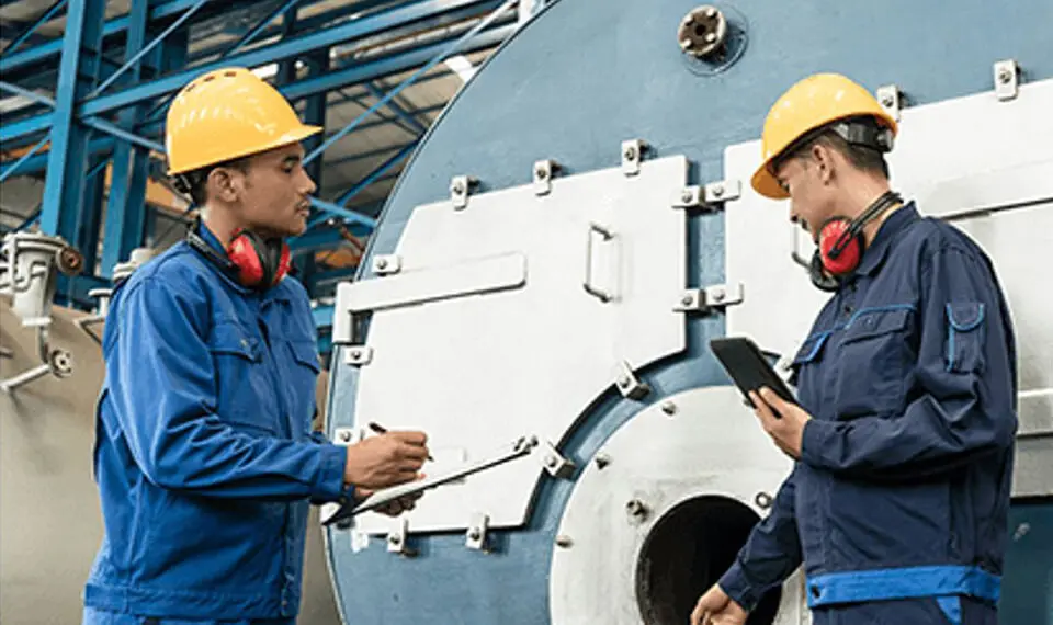 Employees wearing hard hats while inspecting machinery.