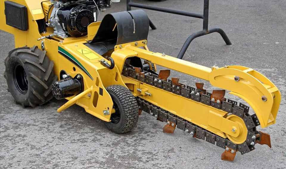 A photo of a trencher parked on asphalt.