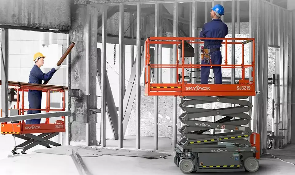 A photo of workers at a construction site using scissor lifts for various tasks.