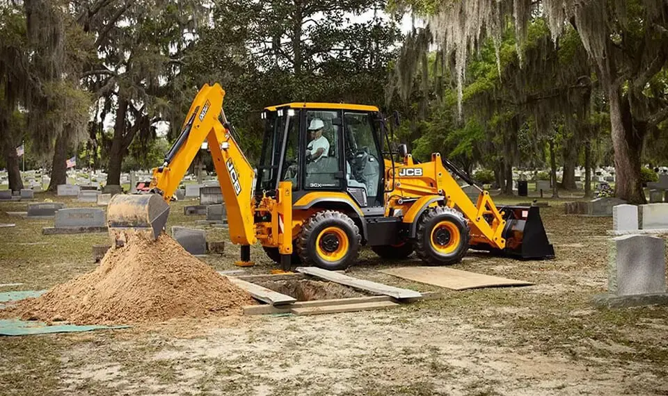 A backhoe being used to dig out a plot at a cemetery.