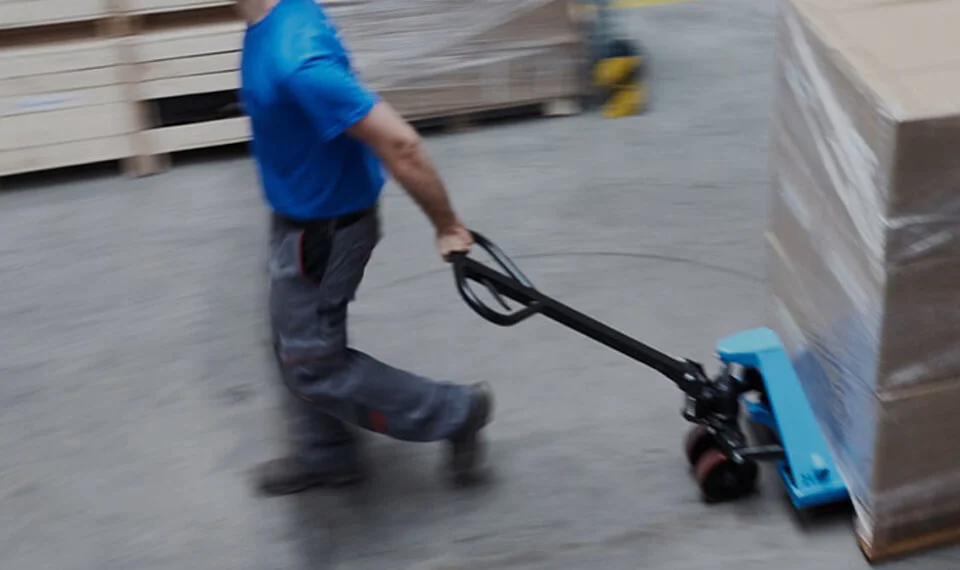 An employee using a pallet jack to move products in a warehouse.